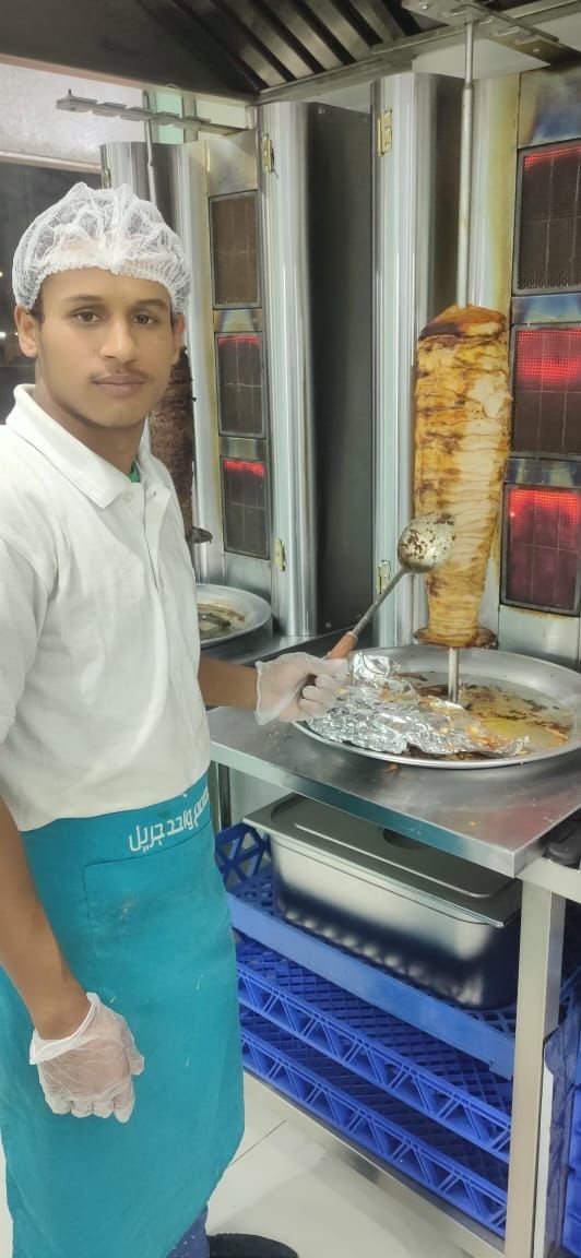 A former trainee working as a cook at a grill counter in a commercial kitchen