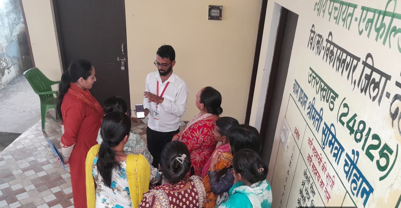 An IIEWS field team explaining a scheme to women gathered outside a gram panchayat building in Mehunwala Khalsa